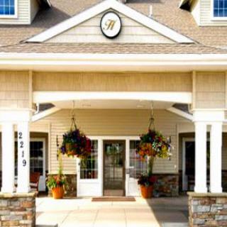 A welcoming entrance adorned with vibrant flowers and a classic clock.