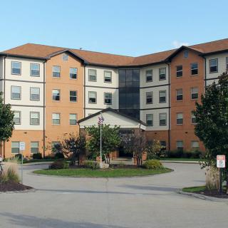 A multi-story residential building with a circular driveway and landscaped front garden.