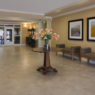A modern lobby with a central table displaying flowers, surrounded by artwork and seating.