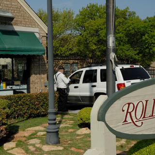A white vehicle parked near a storefront with a green awning and sign.