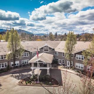 A scenic view of a large residential building with surrounding trees under a partly cloudy sky.
