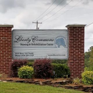 A sign for Liberty Commons Nursing & Rehabilitation Center surrounded by landscaped greenery.