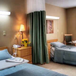 A well-maintained hospital room with two beds and a privacy curtain.