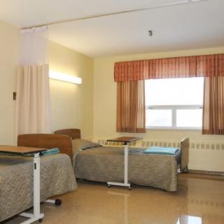 A hospital room with two beds and a window.