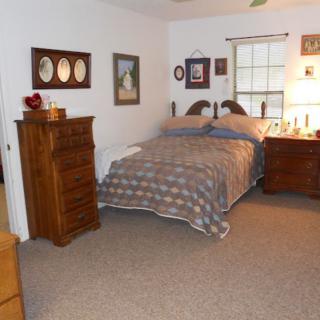 A cozy bedroom with a bed, wooden dresser, and various decorations on the walls.