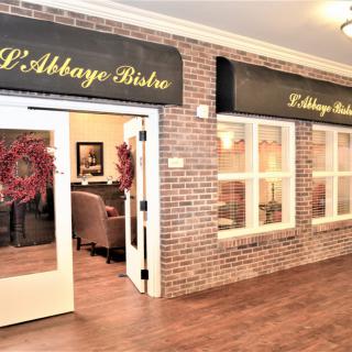 Entrance to L'Abbaye Bistro with brick walls and elegant signage.