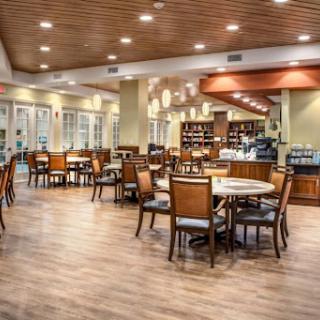 A spacious and inviting dining area featuring wooden tables and chairs, complemented by warm lighting.
