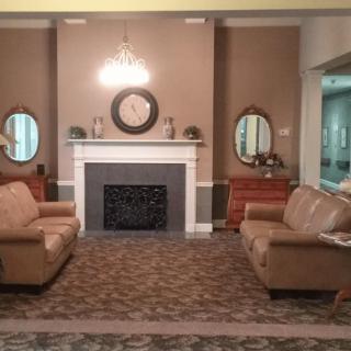 A cozy living room with a fireplace, two sofas, and decorative mirrors.