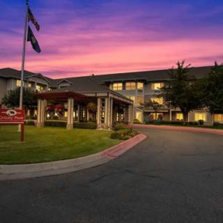 A hotel building with an entrance and flags, set against a colorful sunset sky.