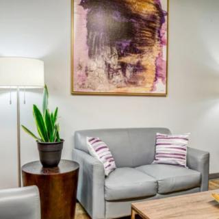 A cozy living room with a grey sofa, abstract artwork, and contemporary decor.