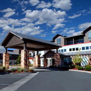 A modern hotel entrance with a covered driveway under a blue, cloudy sky.