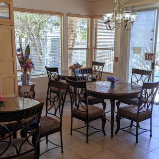 A cozy dining area with multiple tables and chairs, illuminated by natural light from large windows.