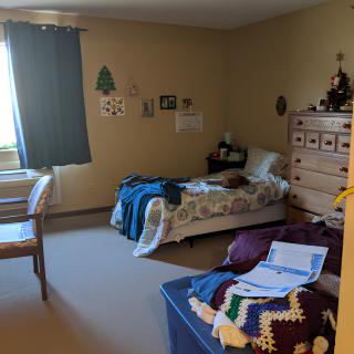 A cozy bedroom with a single bed, a window with curtains, and decorated walls.