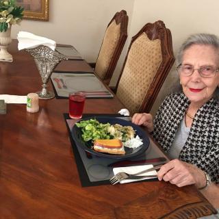 An elderly woman enjoying a meal at a dining table.