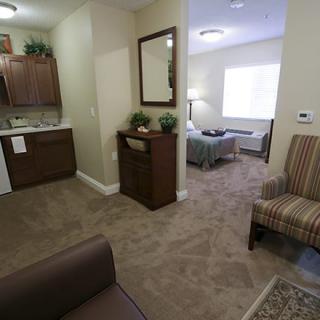 A cozy apartment interior with a view of the living room, kitchenette, and bedroom.