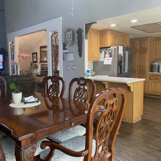 A spacious dining area with a wooden dining table and chairs, adjacent to an open-layout kitchen.