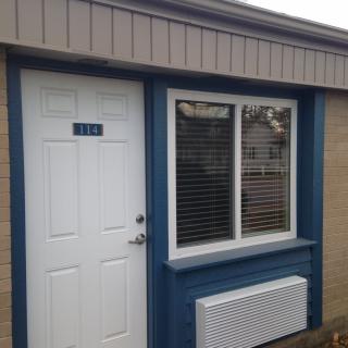 A small building with a white door and window framed in blue.