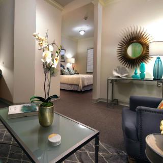 A modern living room featuring elegant furnishings and decor, with a view into a cozy bedroom.