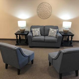 A cozy living room setup with a sofa, two chairs, and ambient lighting.