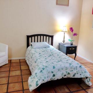 A cozy bedroom with a single bed, nightstand, and decorative flowers.