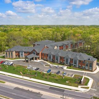 Aerial view of a modern building surrounded by greenery and roads.