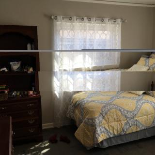 A cozy bedroom with a bed and dresser by the window.
