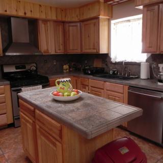 A cozy kitchen with wood cabinets and a central island featuring a fruit basket.