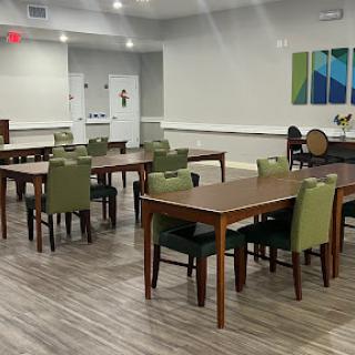 A spacious dining area featuring wooden tables and green chairs, designed with a modern aesthetic.