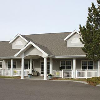 A residential building with a front porch and surrounding trees.