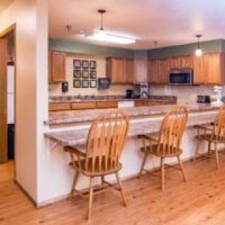 A cozy kitchen interior featuring a wooden dining counter with chairs and modern appliances.