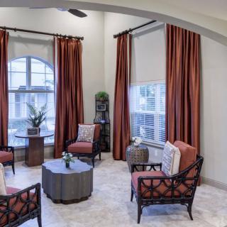 A modern living room with stylish seating and warm-toned curtains.