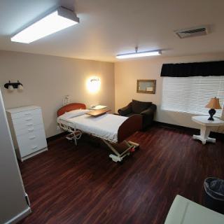 A well-furnished hospital room featuring a medical bed, seating area, and ambient lighting.