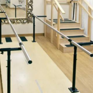A rehabilitation room equipped with parallel bars and stairs for physical therapy exercises.