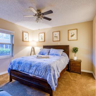 A cozy bedroom with a neatly made bed, artwork on the walls, and a warm ambiance.