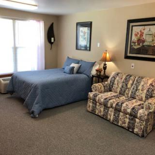A cozy bedroom with a blue bedspread, floral couch, and decorative artwork on the walls.