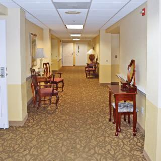 A carpeted hallway with chairs and tables, featuring decorative lighting.