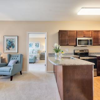 A modern open-plan kitchen and living area with wooden cabinets and comfortable seating.