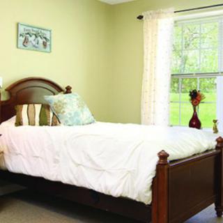 A cozy bedroom with a single bed and a large window adorned with light curtains.