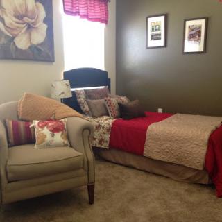 A cozy bedroom featuring a comfortable bed and a stylish armchair, complemented by decorative wall art.