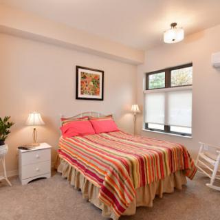 A cozy bedroom featuring a striped bedspread, soft lighting, and modern decor.