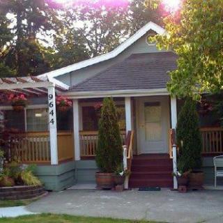 A charming house with a front porch surrounded by trees and greenery in the daytime.