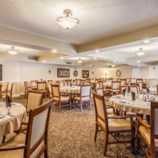 An elegant dining room setup with neatly arranged tables and chairs, featuring soft lighting and tasteful decor.