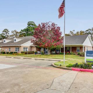 A well-maintained building with an American flag, surrounded by trees and neatly landscaped grounds.