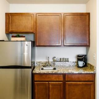 A compact kitchen area with wooden cabinets, granite countertop, and stainless steel appliances.