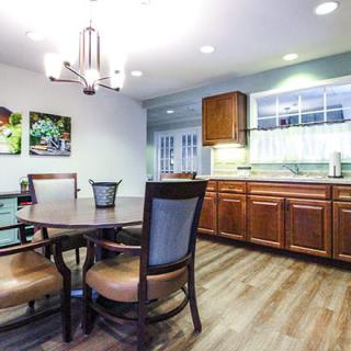 A cozy kitchen and dining area with wooden cabinets, a round dining table, and a chandelier.
