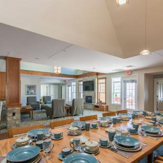 A modern dining area with a beautifully set wooden table, adjacent to a cozy living space.