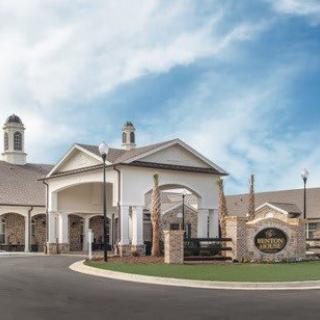 A large building with an arched entrance and a circular driveway under a partly cloudy sky.