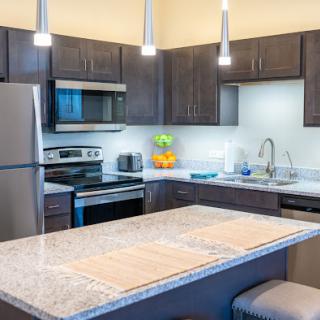 A modern kitchen featuring sleek cabinetry, stainless steel appliances, and elegant pendant lighting.