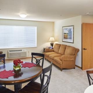 A cozy living room with a sofa, dining table, and large window.