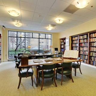 A quiet library study room with tables, chairs, and shelves filled with books.